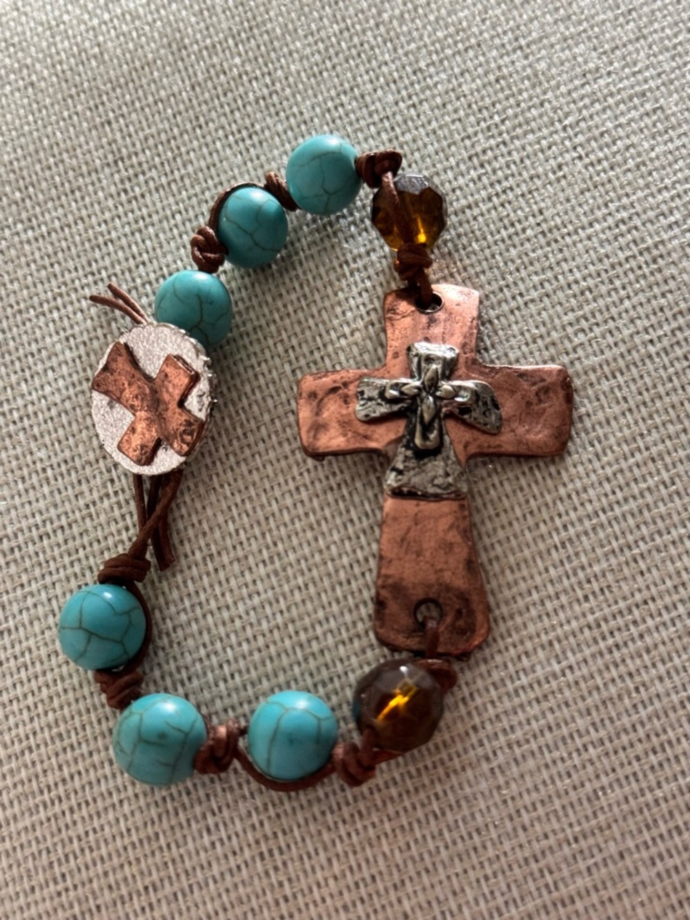 bracelet with turquoise-colored beads and a hammered copper cross charm